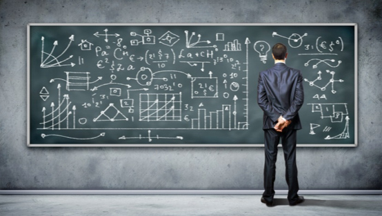 person in suit looking at chalkboard with diagrams